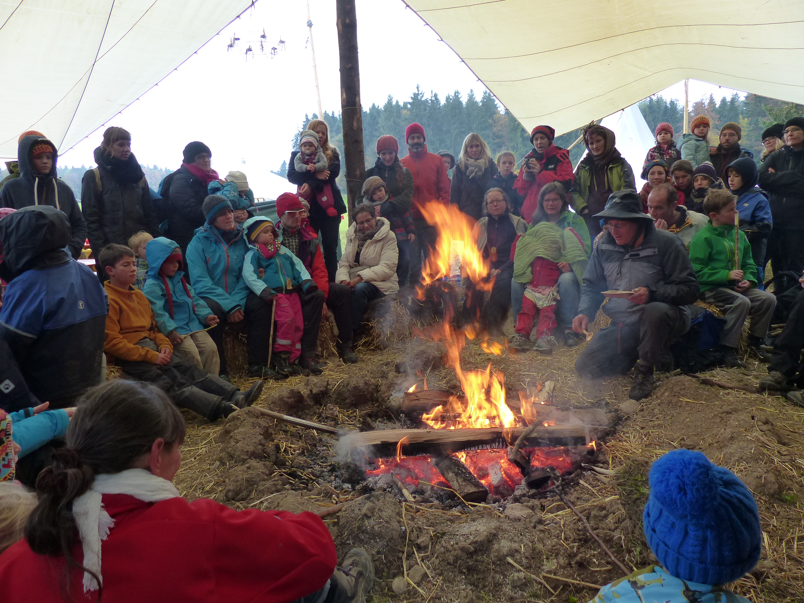 Die Gäste der Feier, des 20-jährigen Bestehens der Genossenschaft Feuervogel sitzen im Kreis um das Feuer